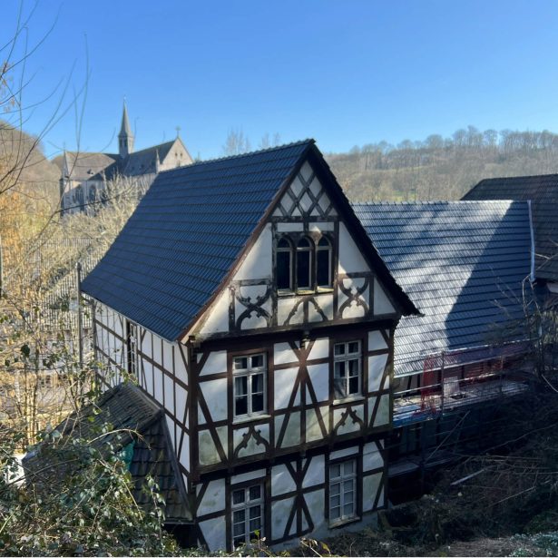 Historisches Fachwerkgebäude des Felsenkellers mit Kirche im Hintergrund