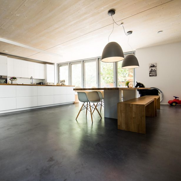 Moderner Wohnbereich mit Küche und sichtbarer Holzdecke im aufgestockten Gebäude