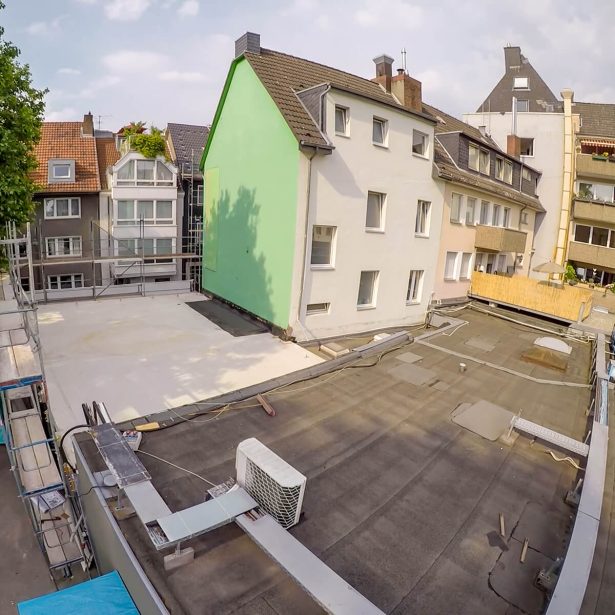 Baustelle der Aufstockung mit vorbereitetem Flachdach und angrenzender Baulücke