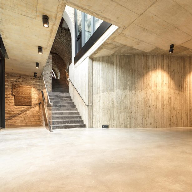 Treppenaufgang zwischen Sichtbeton und historischem Mauerwerk