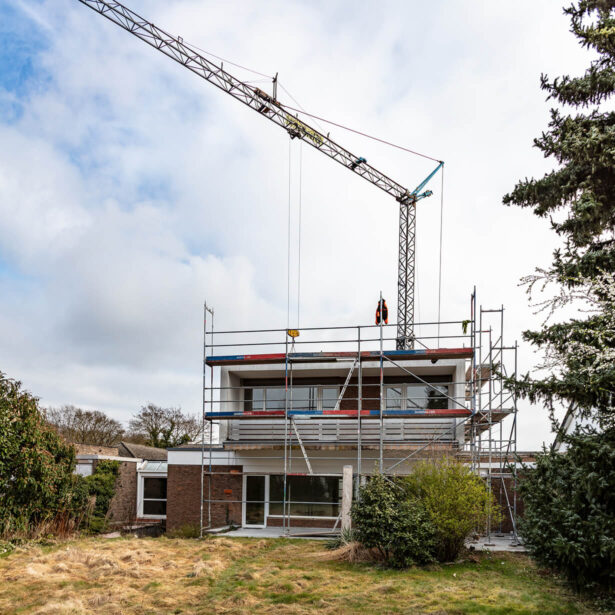 Wohnhaus während der Aufstockung mit Baugerüst und Kran
