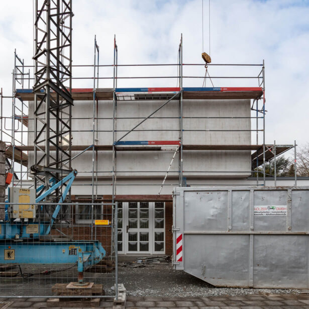 Fassade eines Wohnhauses während der Aufstockung mit Baugerüst und Kran